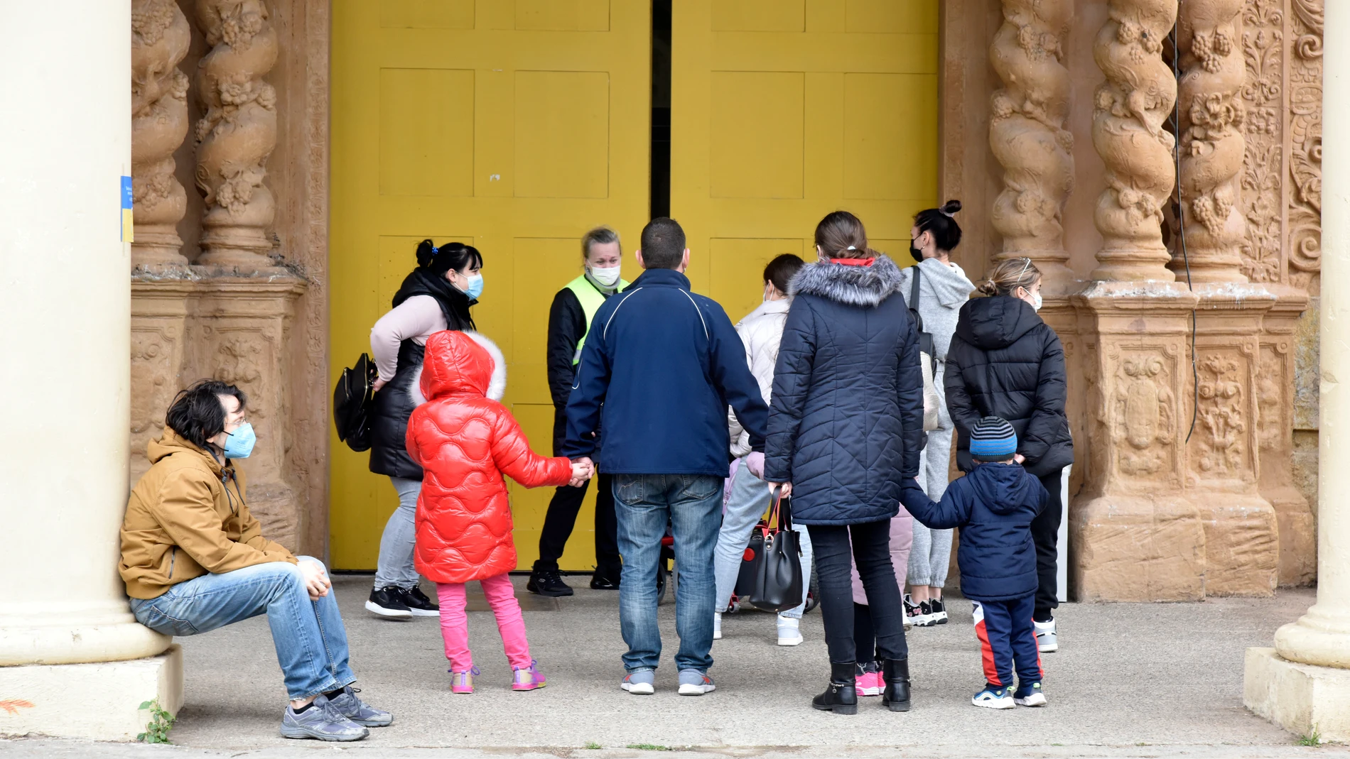 Varias personas refugiadas entran en el palacio de Victoria Eugenia, en la Feria de Barcelona, convertido en centro de recepción y atención de refugiados de Ucrania, en Cataluña (España).