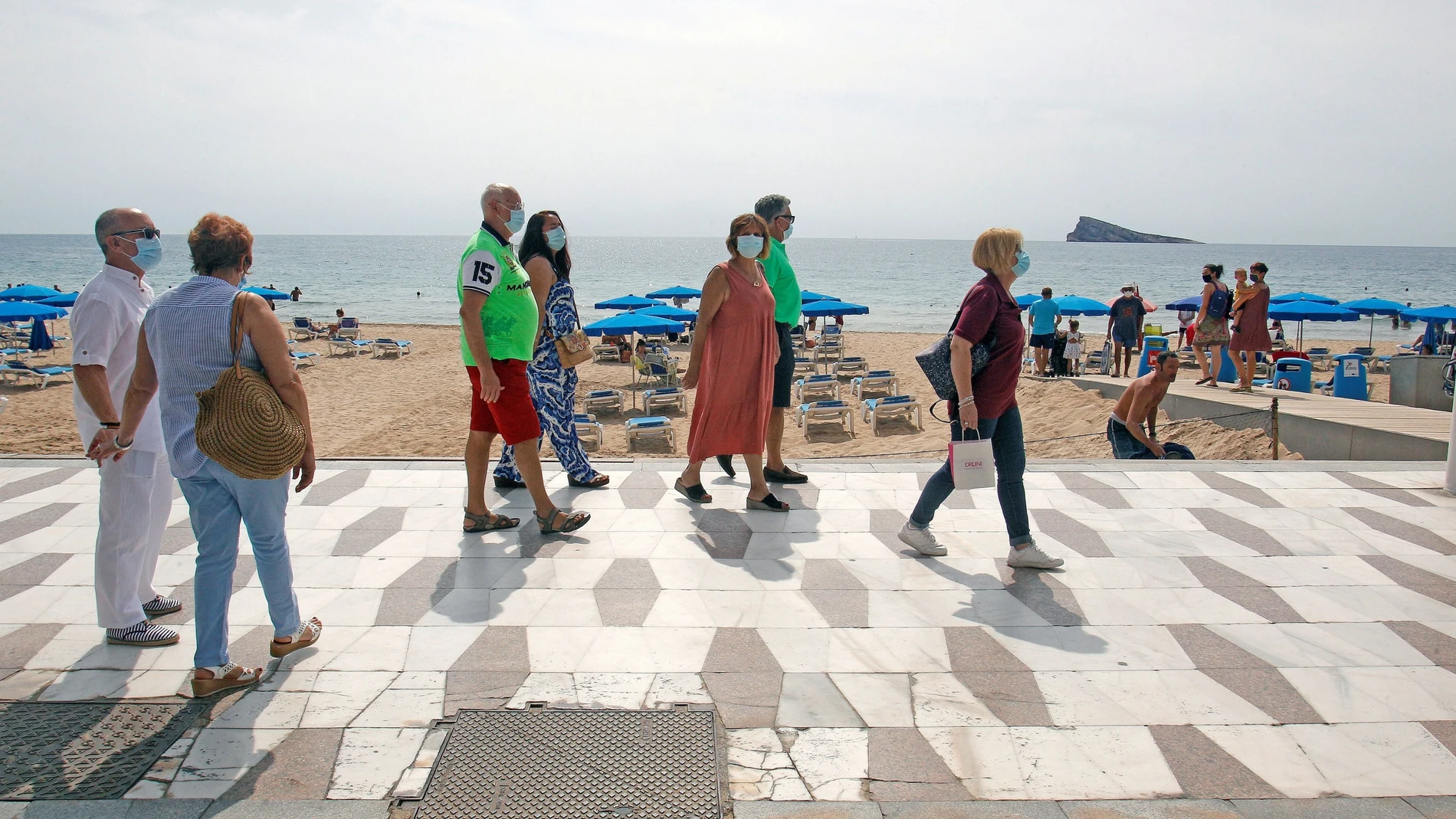 Miembros de una asociación de mayores de Madrid pasean por una playa levantina
