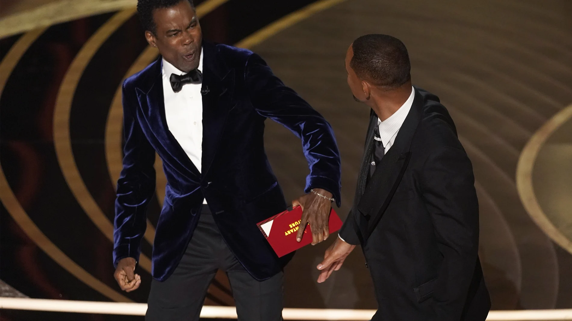Chris Rock recibiendo un puñetazo, en principio pactado, de Will Smith (AP Photo/Chris Pizzello)