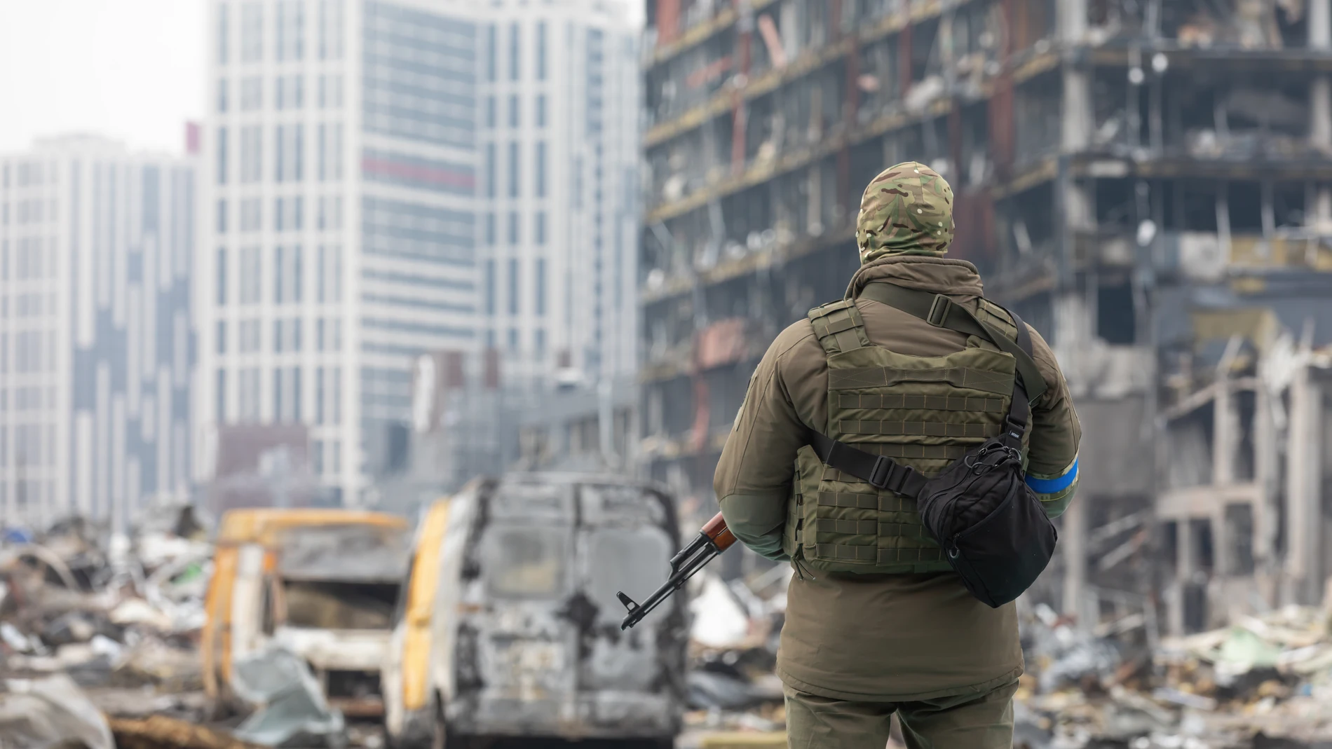 Un soldado con una ametralladora junto a un centro comercial en Kiev destruido con un misil ruso
