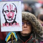Un manifestante con una pancarta de Putin cubierta con una mano manchada de sangre durante una protesta por la guerra en Ucrania en Budapest, Hungría