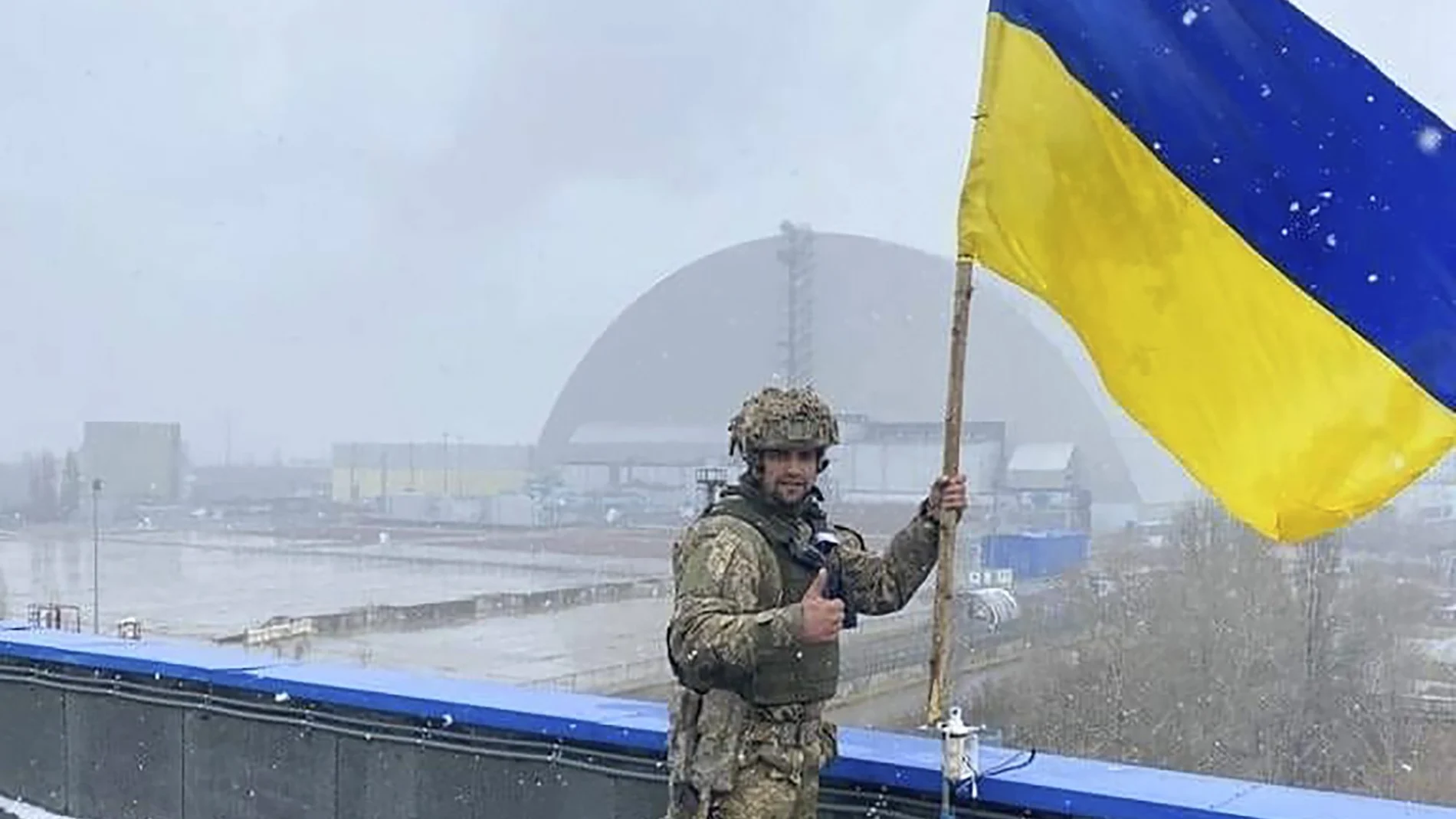 Un soldado ucraniano sostiene la bandera nacional cerca de la central nuclear de Chernóbil