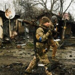 Soldados ucranianos inspeccionan los escombros de una columna de tanques rusos destruida en una carretera en Bucha