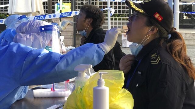 Un sanitario recolecta una muestra de hisopo de los residentes en un área de confinamiento en el distrito de Jingan