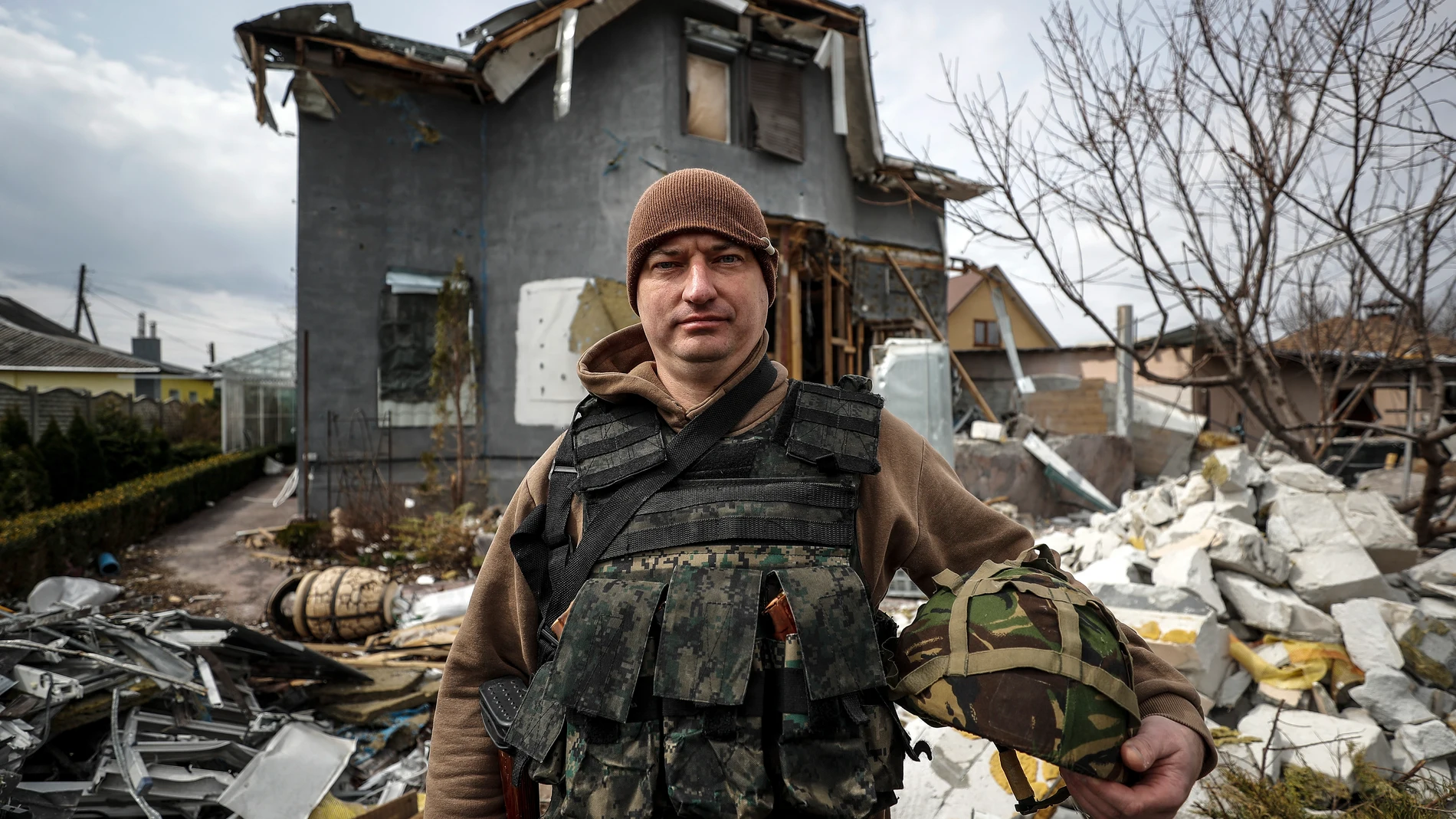 Vlad Malyshev posa con su equipamiento militar ante los restos de su casa, destruida por un misil