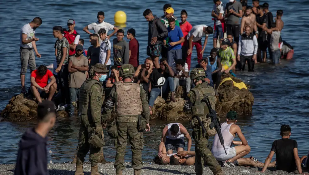Soldados del Ejército de Tierra observan cómo un grupo de inmigrantes alcanzan la playa fronteriza de El Tarajal de Ceuta, el pasado julio