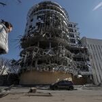 Una mujer camina ante un edificio seriamente dañado por los bombardeos que sufre la ciudad de Járkiv.