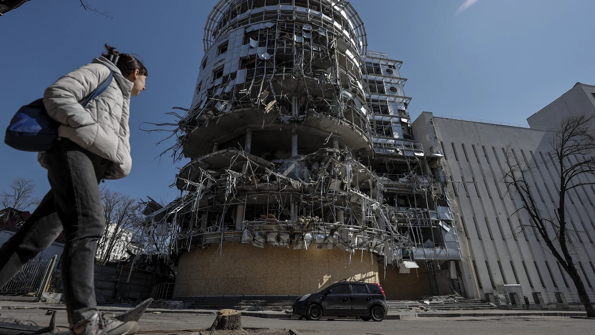 Una mujer camina ante un edificio seriamente dañado por los bombardeos que sufre la ciudad de Járkiv.