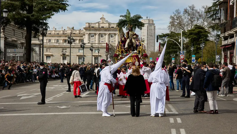 Numerosas personas atienden el paso de la Imagen de Jesús con la Borriquita, por el centro de Madrid