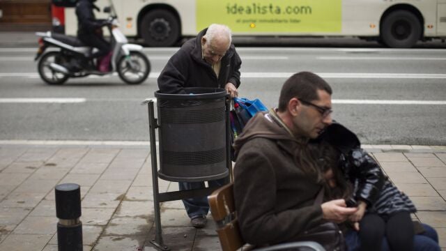 Un señor mayor busca en una papelera de la calle, en Madrid