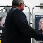 Un hombre pasea frente a los carteles de Le Pen y de Macron en Francia
