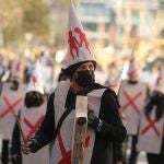 Varios manifestantes vestidos con petos tachados con cruces y capirotes blancos con niños dibujados, durante la manifestación en defensa de los menores tutelados