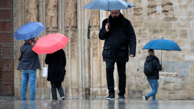 Varias personas pasean bajo la lluvia en Valencia