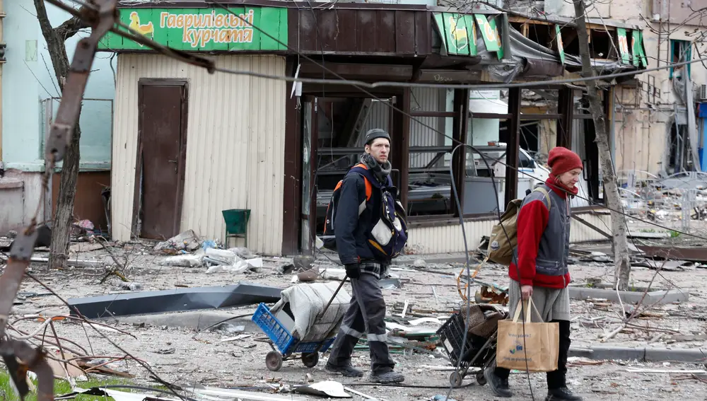 Residentes de Mariupol pasan frente a los edificios destruidos en Mariupol