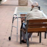 Un hombre de avanzada edad descansa en un banco ubicado en una acera en el pueblo de Sant Lluís, Menorca, Baleares