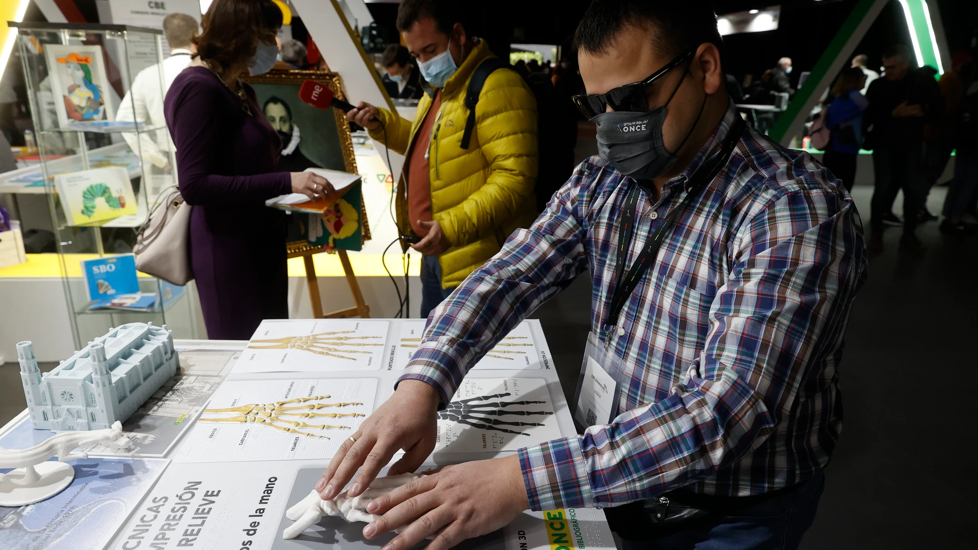 Un invidente palpa la impresión en relieve de los huesos de una mano durante la inauguración de Tifloinnova, la feria internacional de tecnología accesible para personas ciegas en la que se presentan las últimas novedades en inteligencia artificial, en Madrid