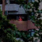 Una mujer se asoma al balcón de su vivienda en un barrio residencial de Shanghái clausurado por la covid