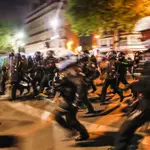 Policías corren hacia los manifestantes que participaban en una manifestación tras el anuncio de los resultados de las elecciones presidenciales francesas en la Place de la Republique de París, en París