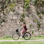 Una joven pasea en bici por el parque del antiguo cauce del Turia cuando el cielo de la Comunitat Valenciana está despejado este viernes