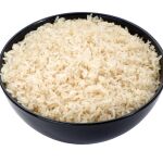 Arroz hervido en un primer plano de tazón negro aislado en blanco | Fuente: Dreamstime