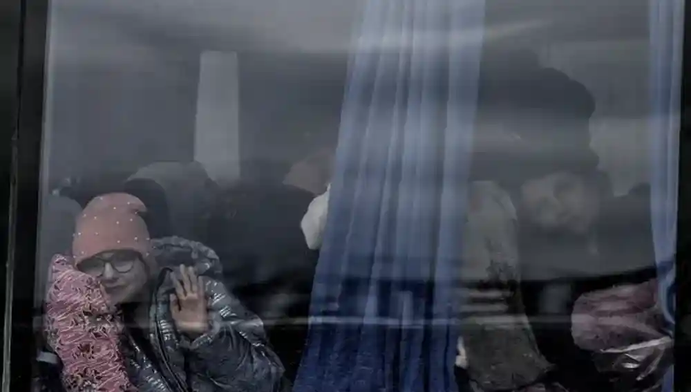Una niña saluda desde un autobús en el que ha llegado a Zaporiyia el pasado 5 de abril. Esta ciudad del centro este de Ucrania se ha convertido en el lugar al que llegan la mayor parte de personas que huyen de Mariupol y las localidades cercanas controladas por el Ejército ruso, pero ahora está cercada