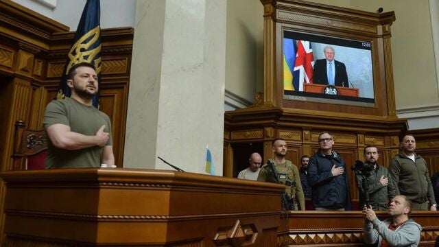 El primer ministro de Reino Unido, Boris Johnson, conectado por videoconferencia, y el presidente ucraniano, Volodimir Zelenski, durante el himno nacional ucraniano en la Rada Suprema