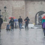 Varias personas con paraguas en una calle de Valencia