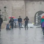 Varias personas con paraguas en una calle de Valencia