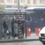 Varios ciudadanos se protegen en una parada de autobús de las lluvias torrenciales de ayer miércoles sobre Murcia capital