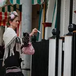 Una mujer enseña su pase al portero para poder acceder a la caseta, en la Feria de Abril de Sevilla. EFE/ José Manuel Vidal