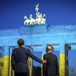 Emmanuel Macron y Olaf Scholz observan la Puerta de Brandenburgo de Berlín, iluminada con los colores de la bandera de Ucrania
