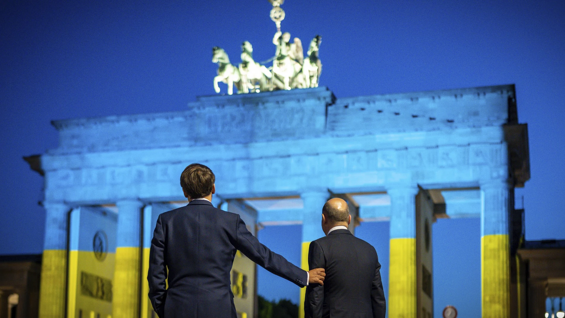 Emmanuel Macron y Olaf Scholz observan la Puerta de Brandenburgo de Berlín, iluminada con los colores de la bandera de Ucrania