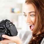 Mujer mirando una cámara de fotos | Fuente: Dreamstime