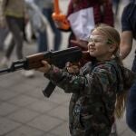Victoria, de 7 años, con un Kalashnikov de plástico apunta contra un retrato de Vladimir Putin en la ciudad ucraniana de Leópolis