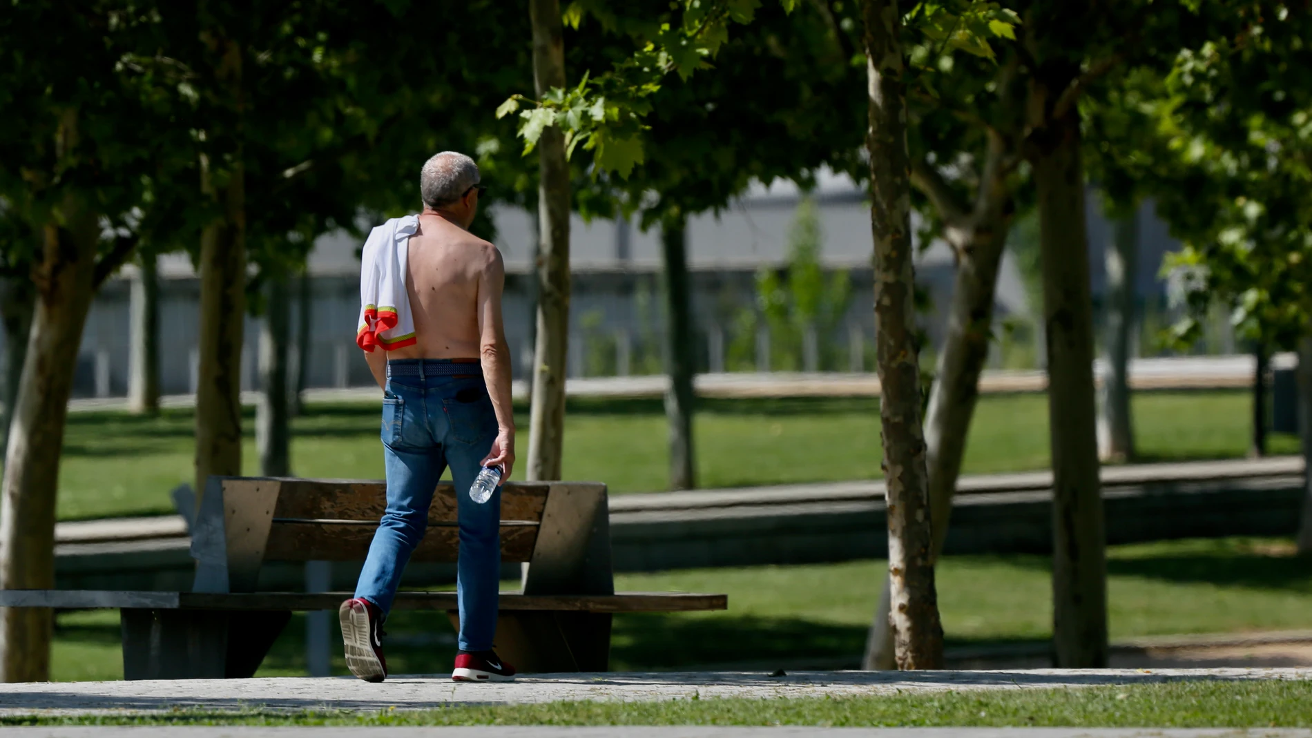 Un hombre camina sin camiseta el día en que España comenzará a sufrir un "importante" episodio cálido con temperaturas de pleno verano. Cézaro De Luca / Europa Press