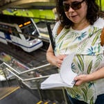 Una mujer invidente en la estación de metro Sevilla posa con una guía de braille del metro de Madrid