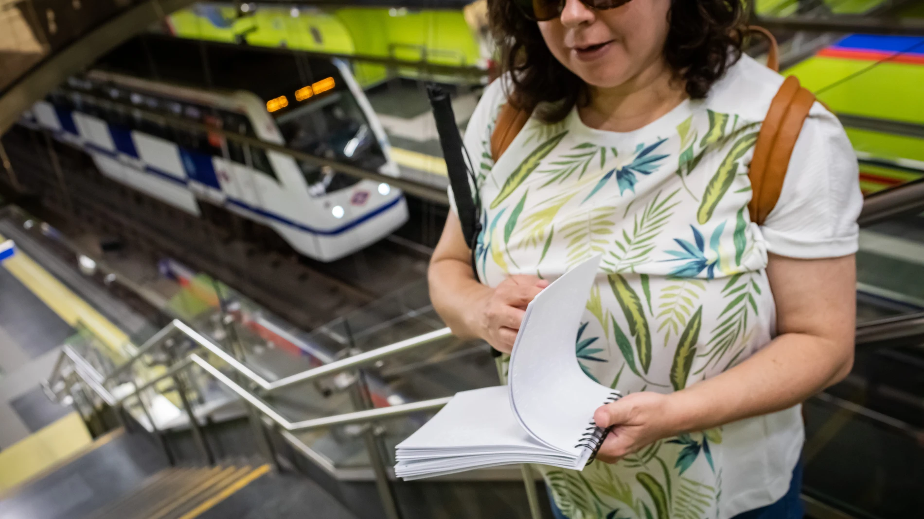 Una mujer invidente en la estación de metro Sevilla posa con una guía de braille del metro de Madrid