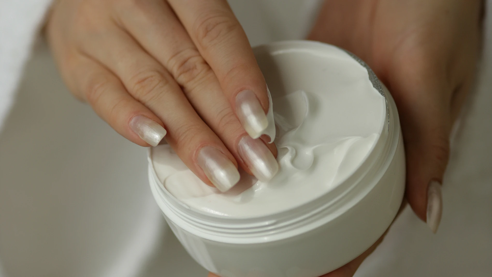 A midsection of a woman holding a box full of white cream. Cream Gel Box Bathrobe Hands Nails Fingers White One Person One Female One Lady One Woman Taking Unknown Emollient Moisturizer Soothing Softening Salving Front View High Angle View Midsection Blurred Differential Focus Vertical Color Image Photography beauty creme handcreme hand finger detail hautpflege koerperpflege people A midsection of a woman holding a box full of white cream.