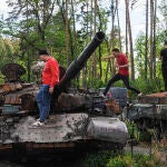 Varias personas caminan sobre tanques rusos destruidos en el pueblo de Dmytrivka, cerca de Kiev