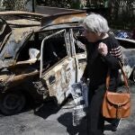 Una anciana pasea junto a un coche calcinado en Sloviansk