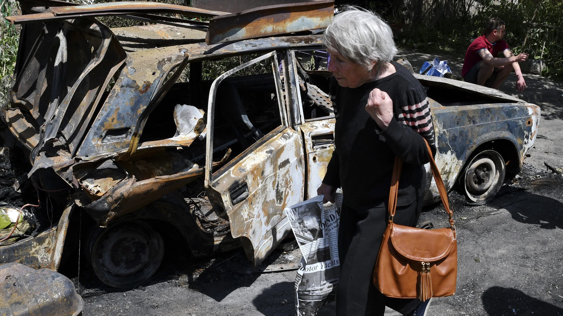 Una anciana pasea junto a un coche calcinado en Sloviansk