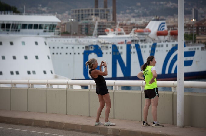 Dos chicas hacen una fotografía frente a la terminal de cruceros del Puerto de Barcelona, visto desde el Puente de la Puerta de Europa