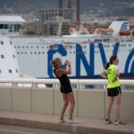 Dos chicas hacen una fotografía frente a la terminal de cruceros del Puerto de Barcelona, visto desde el Puente de la Puerta de Europa