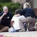 Dos agentes de policía con un familiar de una de las víctimas del tiroteo en el hospital de Tulsa