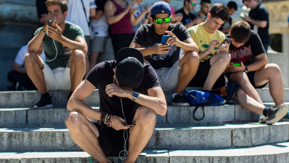 Adolescentes con el móvil en el Estanque del Retiro de Madrid.