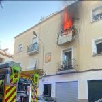 El fuego sale por el balcón de la vivienda, ubicada en el barrio de Triana