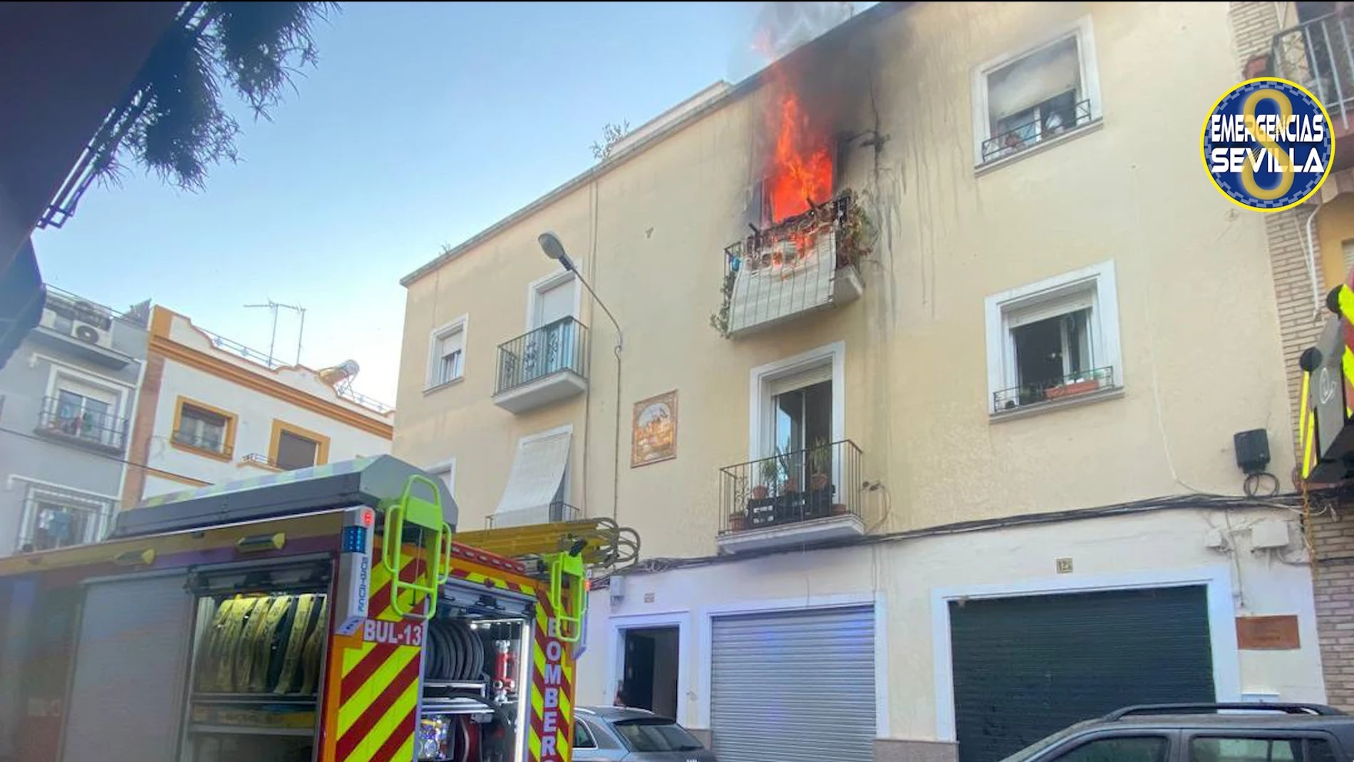 El fuego sale por el balcón de la vivienda, ubicada en el barrio de Triana
