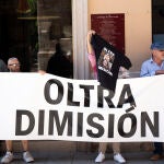 Un grupo de personas sujetan una pancarta en la que se lee: 'Oltra dimisión', a la llegada de Mónica Oltra, a una rueda de prensa
