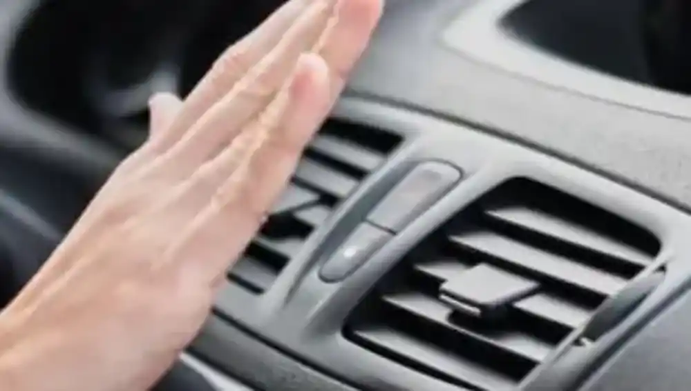 En la imagen, una mano sobre el aire acondicionado de un coche