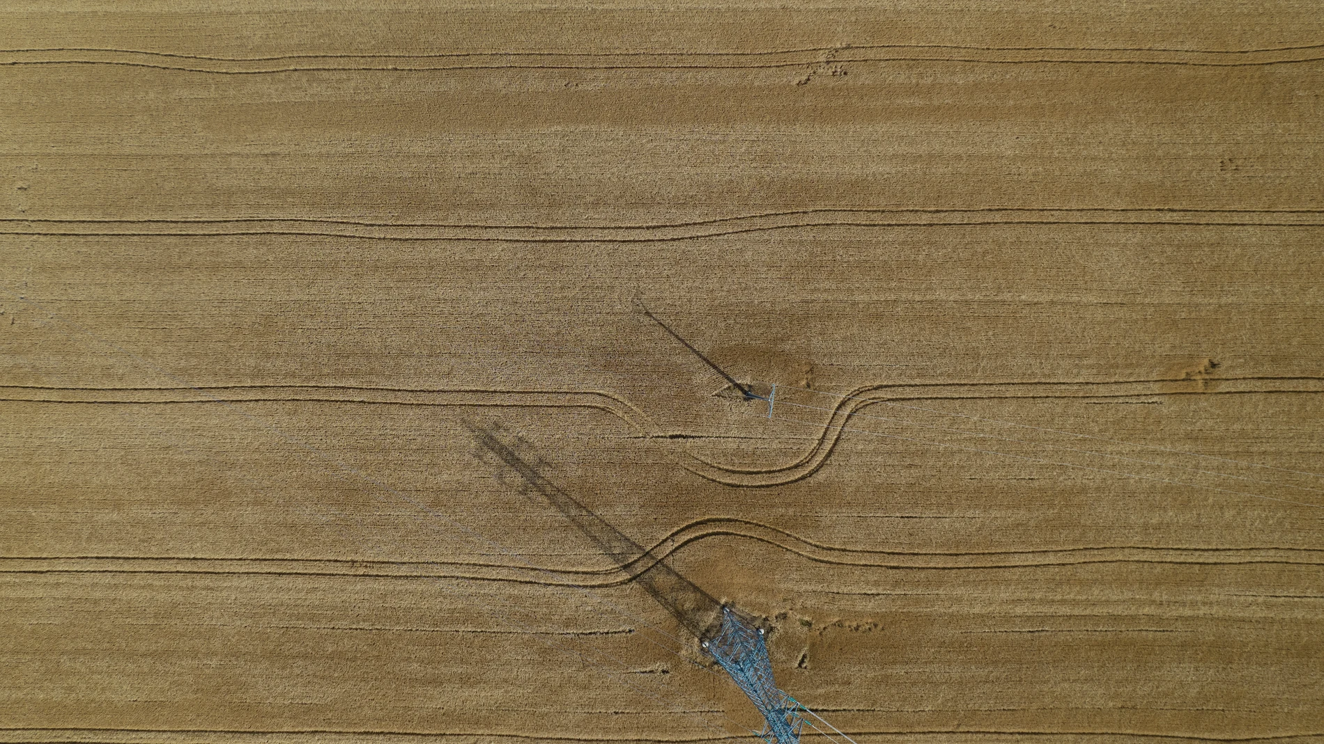 Imagen tomada desde un dron de la sombra de una torre de alta tensión sobre un campo de cereal próximo a la localidad navarra de Aoiz